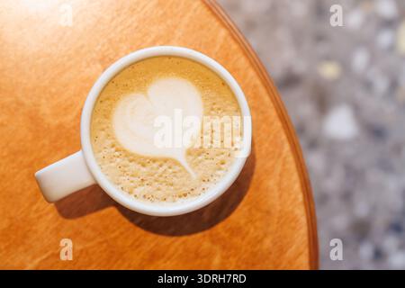 Warmer Cappuccino in einer Tasse mit herzförmigem Latte Art darüber Stockfoto