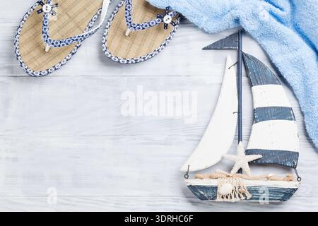 Strand-Accessoires. Flip-Flops, Handtuch und Boot Dekor auf hölzernen Hintergrund. Draufsicht mit Textfreiraum Stockfoto