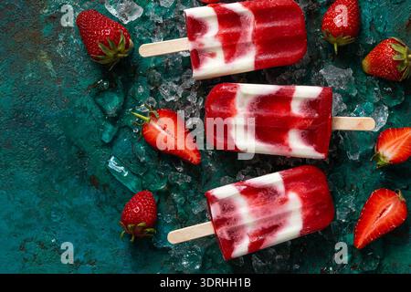 Erdbeeren und Joghurtgelenke, süßes und natürliches Sommereis Beeren Dessert, Blick von oben, dunkelgrüner Backplatz Stockfoto
