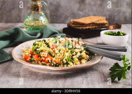 Tabbouleh-Salat mit Bulgur, Tomate und Petersilie auf einem Teller auf dem Tisch Stockfoto