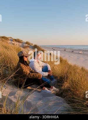 Ein Paar genießt einen ruhigen Blick auf den Sonnenuntergang am Strand in Dänemark Stockfoto