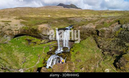 Majestätischer Wasserfall, der durch felsige Klippen stürzt, in der atemberaubenden Landschaft Islands Stockfoto