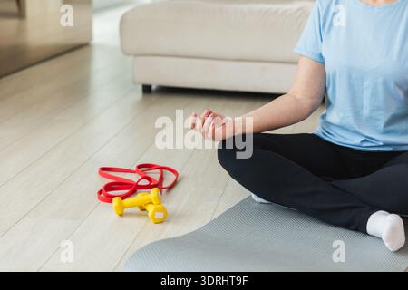 Yoga-Achtsamkeitsmeditation. Ältere reife Frau, die zu Hause Yoga praktiziert. Hände in Kinnmudra-Geste. Eine Erwachsene alte Dame sitzt drinnen Stockfoto