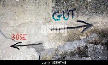 Ein Bild mit einem Wegweiser, der in zwei verschiedene Richtungen auf Deutsch zeigt. Eine Richtung weist auf das Gute, die andere auf das Böse hin. Stockfoto