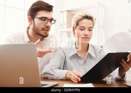 Diskussion zwischen zwei Personen über Arbeitsdokumente in einer Büroumgebung während des Tages Stockfoto