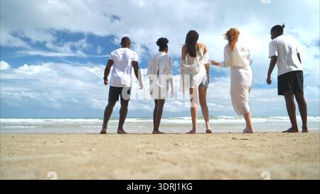 Gruppe von verschiedenen Freunden, die Spaß am Strand haben, spazieren gehen und in den Wellen planschen Stockfoto