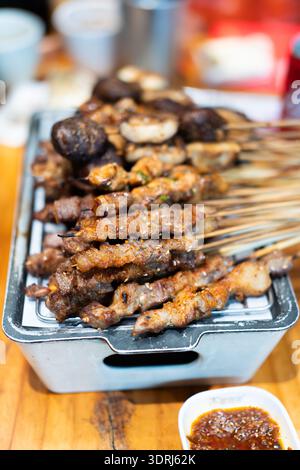 Indonesische Satay-Spieße, gegrillt auf Metalltablett mit Erdnusssauce, Street Food Szene Stockfoto