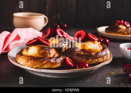 Flauschige Brötchen mit Hüttenkäse und Kirschen auf einem Teller auf dem Tisch Stockfoto