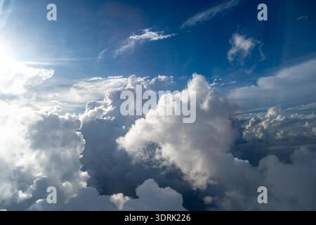 Majestätische Wolken, die von der Sonne beleuchtet werden, schaffen einen dramatischen Himmel, der von oben betrachtet wird. Das helle Sonnenlicht steht im Kontrast zum tiefen Blau Stockfoto
