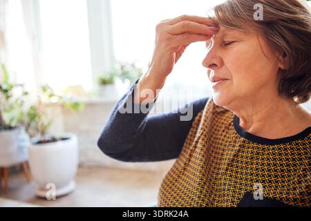 Nahaufnahme einer älteren Frau mit Kopfschmerzen. Die reife Dame hat ihre Augen geschlossen Stockfoto