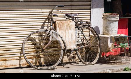 Altes Fahrrad, das sich unter warmem Sonnenlicht an eine Wand lehnt. Stockfoto