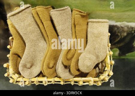 Mehrere süße, handgefertigte Wollsocken liegen in einem Korb Stockfoto