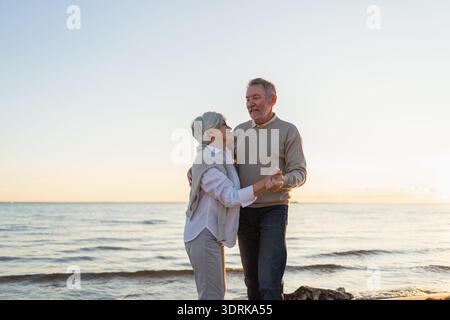 Bleiben Sie in Bewegung. Romantisches älteres Ehepaar, das gemeinsam am Strand im Freien tanzt. Glücklich lächelnde Familie pensionierte Mann Frau Stockfoto