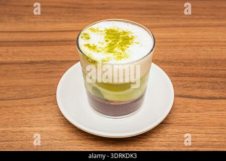 Die moderne Verschmelzung von Ost und West: Ein Matcha Latte mit perfekt definierten Schichten, in denen aufgeschäumte weiße Milch in einem glatten Verlauf vermischt wird Stockfoto