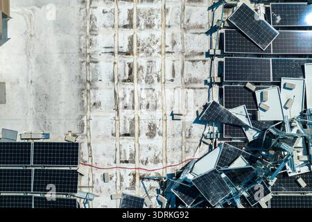 Draufsicht der durch den Hurrikan Ian zerstörten Photovoltaik-Solarpaneele, die auf dem Dach des Industriebaues zur Erzeugung von ökologischem Strom montiert sind Stockfoto