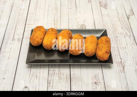 Süße Kroketten, gefüllt mit Schokolade oder Pudding, paniert und frittiert, mit Puderzucker bestäubt und als ungewöhnliches Dessert serviert Stockfoto