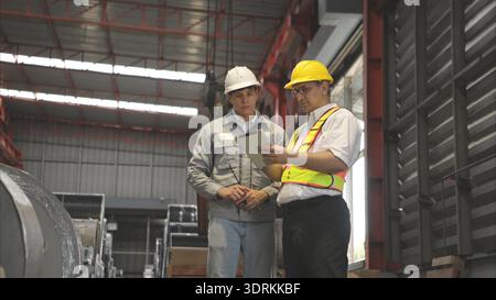 Industriearbeiter, der in einem großen Metallrohr in einer Fabrik inspiziert Stockfoto