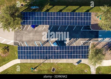 In die städtische Infrastruktur integrierte Solarstromerzeugung. Photovoltaikpaneele als Schattendach über dem Parkplatz mit geparkten Autos installiert Stockfoto