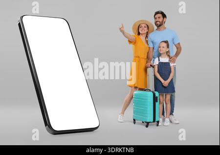 Familie, die ein großes Smartphone mit leerem Bildschirm auf grauem Hintergrund betrachtet. Mutter zeigt auf Gerät Stockfoto