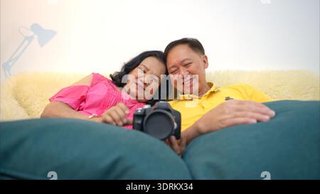 Im Urlaub entspannt sich ein älteres Paar auf dem Sofa und sieht in der Kamera ein Bild Stockfoto