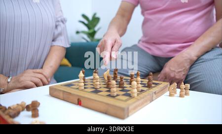 Seniorenpaar spielt gemeinsam Schach zu Hause, genießt Freizeit und geistige Bewegung Stockfoto
