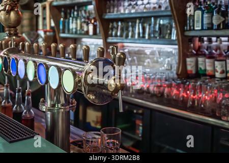 Eine Reihe von Bierzapfen vom Fass an einem Theken vor verschwommenen Spirituosenflaschen und Gläsern in einer gemütlichen lokalen Bar, Vieille Ville oder der Altstadt, Nizza, Frankreich Stockfoto