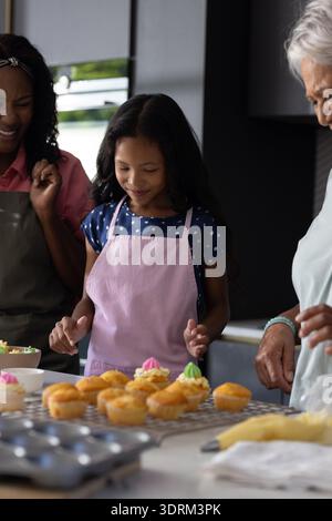 Zusammen Cupcakes backen, drei Generationen lächeln und die Familie in der Küche verbringen. Großeltern, Zweisamkeit, Nachtisch, Hap Stockfoto