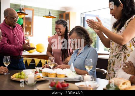 Seniorenfreunde feiern zu Hause Geburtstag, klatschen und lächeln um den Tisch herum. Feier, Freundschaft, Zweisamkeit, Party, CA Stockfoto