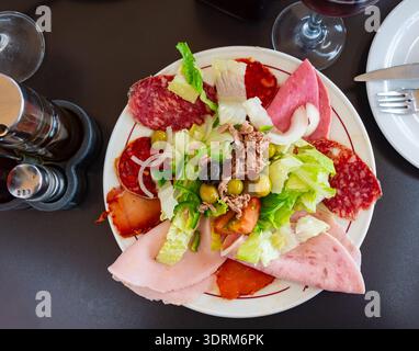 Scheiben salame Cotto affumicato, krustetes Gemüse und Salatblätter - traditioneller iberischer Salat Stockfoto