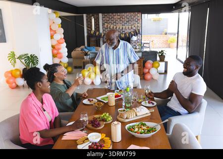 Familie genießt festliche Mahlzeiten zusammen, lacht und toast mit Getränken. Feiern, Abendessen, Zweisamkeit, Treffen, Stockfoto