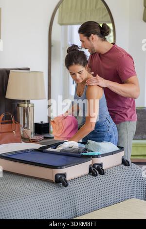 Ein Paar packt Koffer auf dem Bett und bereitet sich auf die gemeinsame Hochzeitsfeier vor. Reisen, Romantik, Flitterwochen, Gepäck, Glück, Stockfoto