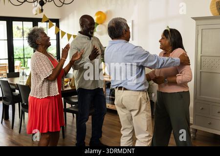 Ältere Freunde feiern zu Hause Geburtstag, lächeln und umarmen vor Freude. Feier, Freundschaft, Glück, Party, Senior, Stockfoto