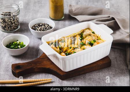 Gebackene Teigtaschen mit Kräutern und Sauce in einer Pfanne auf dem Tisch Stockfoto