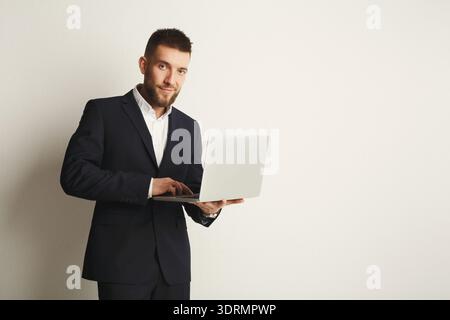 Business Professional arbeitet mit einem Notebook in einem einfachen Bürobereich mit neutralem Hintergrund und heller Stimmung Stockfoto