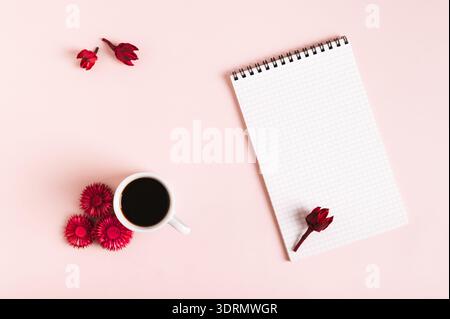 Tasse Kaffee, getrocknete Blumen und offenes Notizbuch auf rosafarbenem Hintergrund von oben Stockfoto