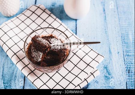 Hausgemachter süßer Kuchen in einem Becher, der in der Mikrowelle auf dem Tisch gemacht wurde Stockfoto