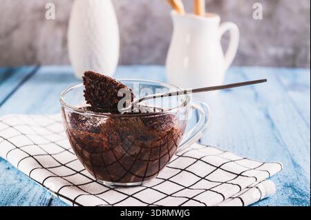 Schokoladen-Cupcake mit Puderzucker in einem Becher auf dem Tisch Stockfoto