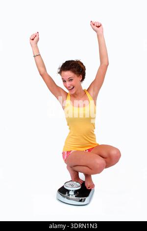 Junge Frau auf der Personenwaage Stockfoto