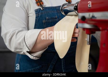 Nahaufnahme des Küchenchefs, der die Pasta-Maschine in der Küche benutzt. Stockfoto