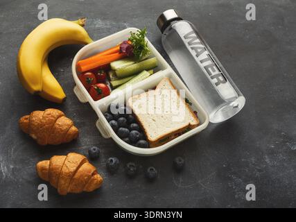 Gesunde Lunchbox mit Obst, Gemüse und Sandwich für eine nahrhafte Mahlzeit am Arbeitsplatz oder in der Schule Stockfoto