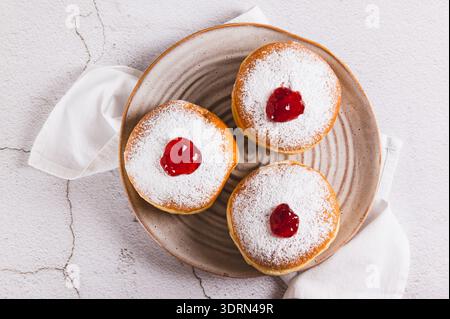Nahaufnahme von süßen Donuts in Puderzucker mit Marmelade auf einem Teller auf dem Tisch Stockfoto