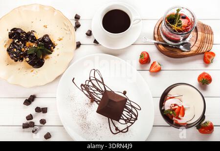 Desserts und Kaffee auf einem Tisch mit frischen Erdbeeren und Schokoladenstückchen Stockfoto