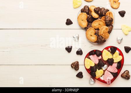Sammlung herzförmiger Bonbons und Kekse auf einem Holztisch Stockfoto