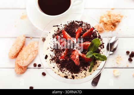 Köstliches Dessert mit Erdbeeren und Kaffee auf weißem Holztisch Stockfoto