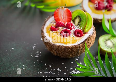 Köstlicher Mango-Kokos-Smoothie mit Früchten und Beeren, serviert in frischer Kokosnuss. Gesunde vegane Rohkost Stockfoto