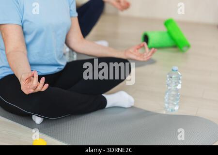 Yoga-Achtsamkeitsmeditation. Älteres Ehepaar, das zu Hause Yoga praktiziert. Hände in Kinnmudra-Geste. Der alte Ehemann sitzt Stockfoto