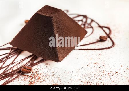 Schokoladenstruktur mit Kaffeebohnen und Kakaokunst auf weißer Oberfläche in kreativem Ambiente Stockfoto