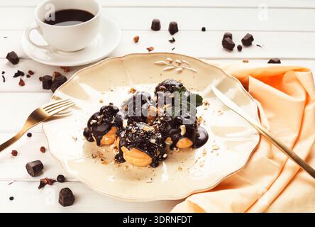 Köstliches Dessert auf einem Teller mit Kaffee und Schokoladensauce in gemütlicher Umgebung Stockfoto