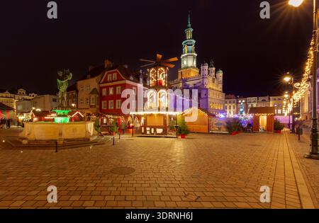 Festlicher Abendblick auf Weihnachtsmarkt Stände und beleuchtete Windmühle auf dem Alten Marktplatz in Posen, Polen. Historische farbenfrohe Stadthäuser im B Stockfoto
