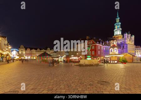 Festlicher Abendblick auf Weihnachtsmarkt Stände und beleuchtete Windmühle auf dem Alten Marktplatz in Posen, Polen. Historische farbenfrohe Stadthäuser im B Stockfoto